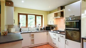 A kitchen with white cabinets, a stove, an oven, a sink, and a window. - The Nest | Large Family Home! (Cowplain)