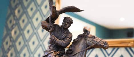 A bronze statue of a man on horseback with an eagle, set against a patterned wall.