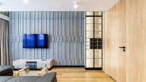 Una sala de estar moderna con un televisor de pantalla plana montado en una pared con textura, un mueble de madera y una mesa de centro de vidrio.