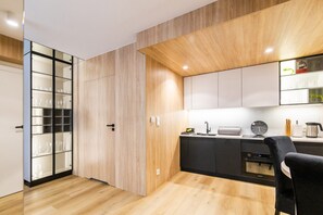 A modern kitchen with wooden cabinetry, a black countertop, and a built-in oven. - Luxury 3-room apartment by the beach (Rowy)