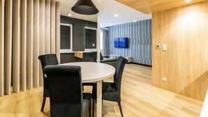 Una sala de conferencias moderna con una mesa redonda y sillas, una televisión y un techo de madera.