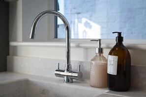 A bathroom with a chrome faucet, a soap dispenser, and a bottle of soap on a countertop. - Pet friendly  direct water access  3bed sleeps 6 (Fareham)