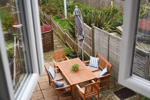 A wooden patio with a table and chairs, surrounded by a wooden fence and various plants. - Pet friendly  direct water access  3bed sleeps 6 (Fareham)