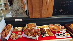 Una exhibición de panadería con panes, pasteles y postres sobre una mesa cubierta con mantel rojo.
