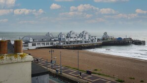 Un paseo marítimo con un muelle que se adentra en el mar, con una montaña rusa y un edificio con cúpula.