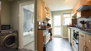 A compact kitchen with a washing machine, a microwave, and a stove. - Parkside Haven | 2BR w/Off-Road Parking (Hampshire)