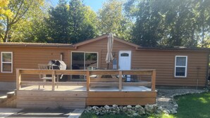 A wooden deck with a bench, a covered table, and a grill area.
