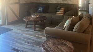 A cozy living room with a wooden wall clock, a sofa, and two coffee tables.