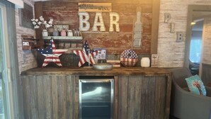 A rustic bar area with wooden accents, a refrigerator, and American flag decorations.