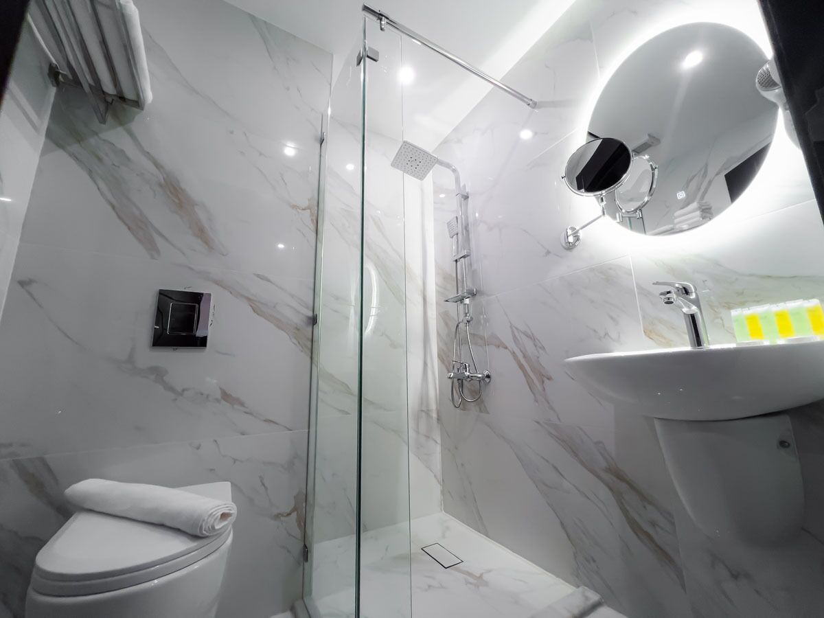 Ein modernes Badezimmer mit einer Duschkabine, einer Toilette und einem Waschbecken mit Spiegel.