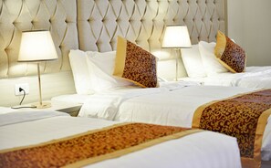 A hotel room with a tufted headboard, two bedside lamps, white bedding, and decorative pillows. - Petra Premium Hotel (Wadi Musa)