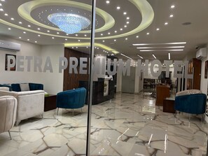 A hotel lobby with a marble floor, blue armchairs, a chandelier, and a reception desk. - Petra Premium Hotel (Wadi Musa)