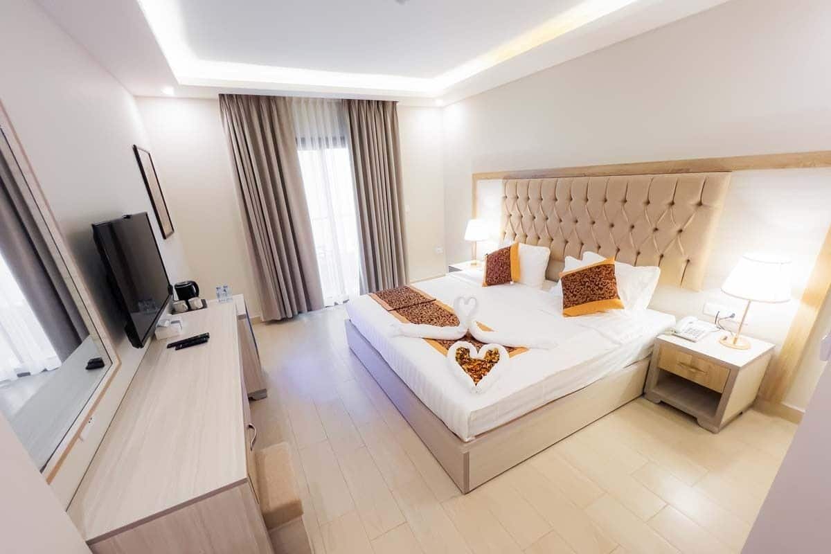 A hotel room with a large bed, a desk, a television, and a nightstand.