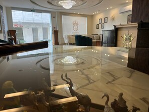 A lobby with a marble reception desk, a chandelier, and a wall-mounted emblem.