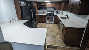 A modern kitchen with dark wood cabinets, stainless steel appliances, and a white marble countertop. - Charming 4-bedroom Lake house on Lake Ripley in Cambridge (Cambridge)