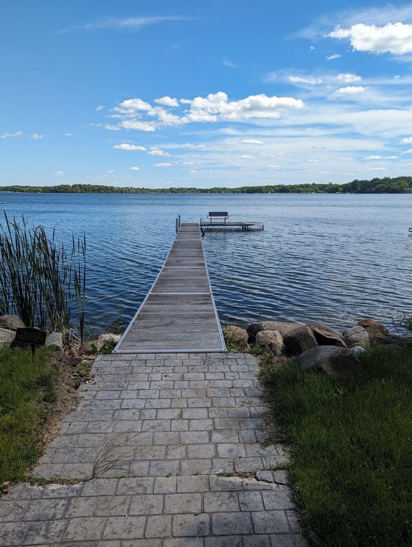A wooden dock extending into a calm lake, surrounded by rocks and grass. - Charming 4-bedroom Lake house on Lake Ripley in Cambridge (Cambridge)