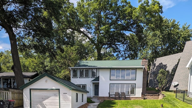 A two-story house with a green roof, a garage, and a well-maintained lawn. - Charming 4-bedroom Lake house on Lake Ripley in Cambridge (Cambridge)