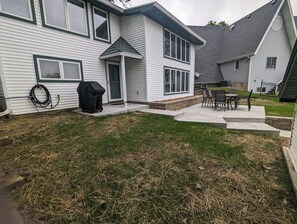 A residential house with a covered patio, a barbecue grill, and a small outdoor seating area. - Charming 4-bedroom Lake house on Lake Ripley in Cambridge (Cambridge)
