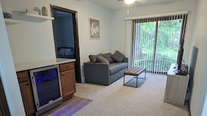 A living room with a grey sofa, a coffee table, a TV, and a fireplace. - Charming 4-bedroom Lake house on Lake Ripley in Cambridge (Cambridge)