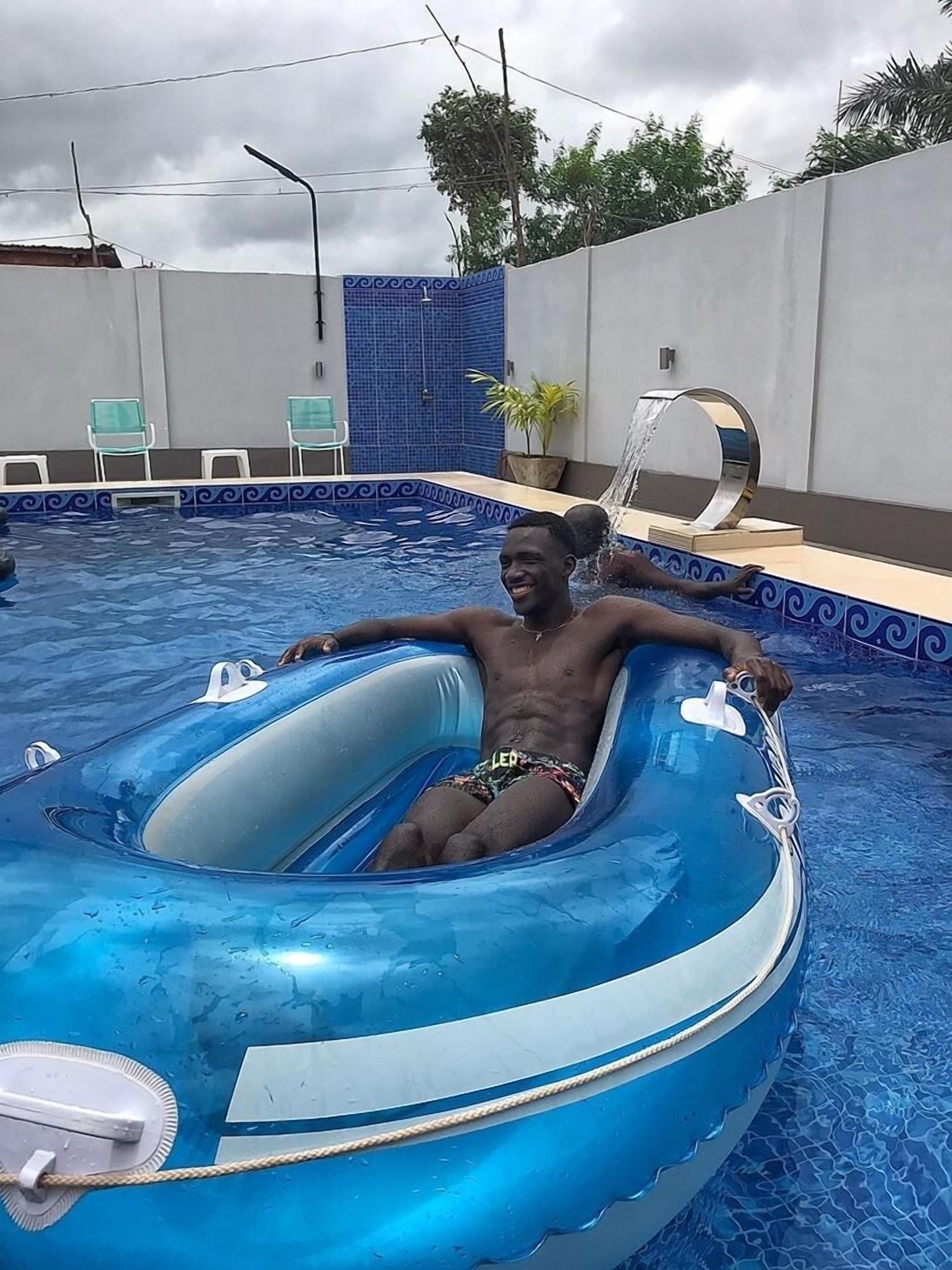 Eine Person in einem blauen aufblasbaren Pool mit einer blau-weißen Fliesenleiste.