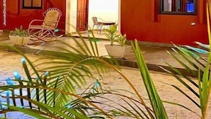 A two-story house with a porch, a rocking chair, and potted plants. - RESIDENCE AINA (Abomey-Calavi)