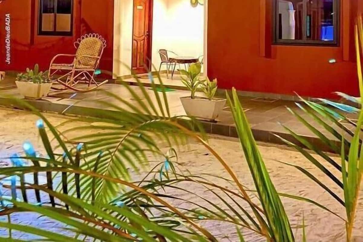 Ein zweistöckiges Haus mit Veranda, Schaukelstuhl und Topfpflanzen.