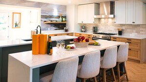 Una cocina moderna con una isla grande, taburetes de madera y vista al área de estar.