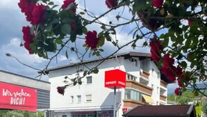 A building with a red sign, a small wooden structure, and a fence. - Apartment mit Gartenblick (Aldrans)