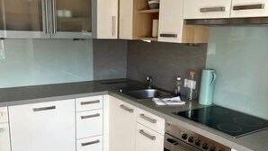 A modern kitchen with white cabinets, a black countertop, a stainless steel stove, and a built-in oven. - Apartment mit Gartenblick (Aldrans)