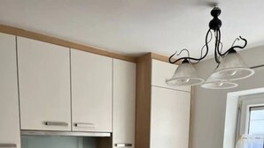 A modern kitchen with white cabinets, a stove, oven, and a coffee maker. - Apartment mit Gartenblick (Aldrans)