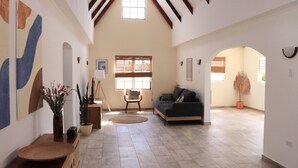 A spacious living area with a high ceiling, a large window, a sofa, and a painting on the wall. - NEW! Villa La Brisa Aruba│Beautiful&Relaxing: Private pool,8-Min Stroll to Beach (Noord)