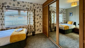 Une chambre d’hôtel avec deux lits, un grand miroir et une porte coulissante.