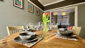 Une table à manger dressée avec des bols noirs, des verres à vin et un vase de tulipes.