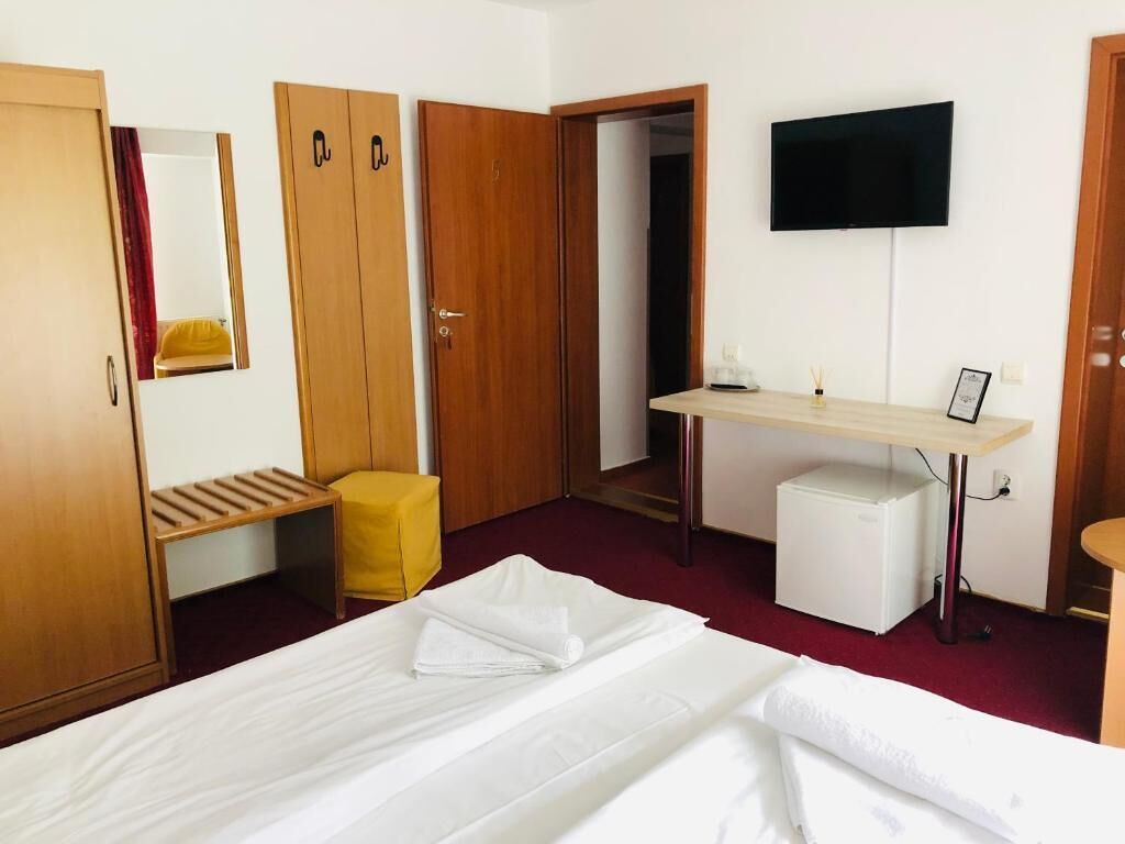 A hotel room with a bed, a desk, a television, and a wardrobe.