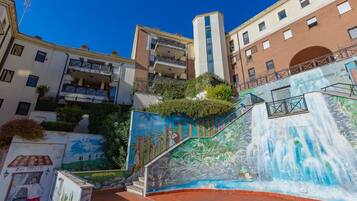 Un edificio a più piani con un murale raffigurante una cascata e vegetazione sulla facciata esterna.
