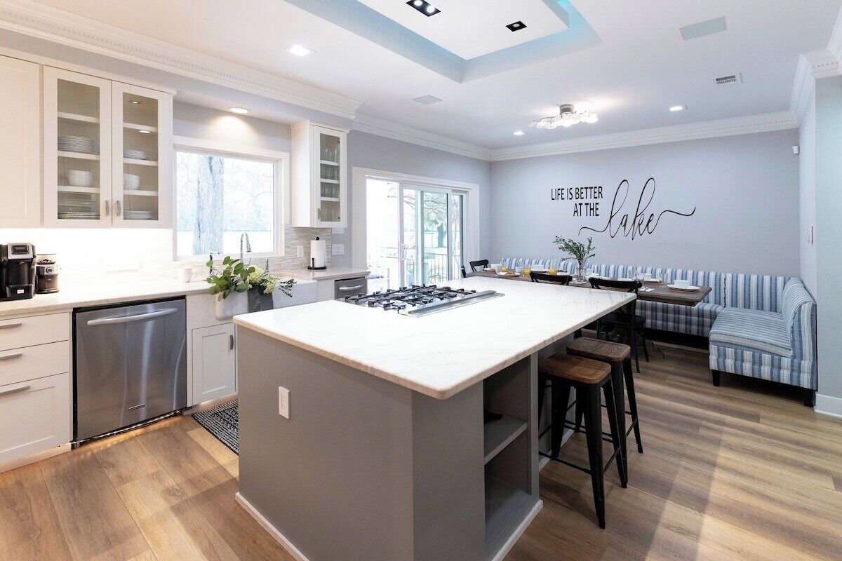 A modern kitchen with a central island, built-in cabinets, and a seating area with a bench and stools.