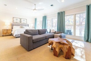 Un salon spacieux avec un canapé gris, une table basse en bois et une grande fenêtre agrémentée de rideaux.