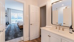 Un bany d'hotel amb un mirall gran, un lavabo i una zona de dutxa.