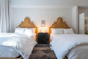 Une chambre d’hôtel avec deux lits, une table de chevet et une lampe fixée au mur.