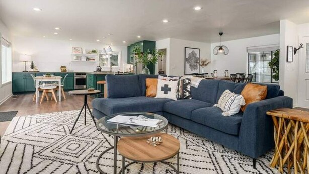 Een moderne woonkamer met een blauwe bank, een salontafel en een kamerbreed tapijt met een patroon.