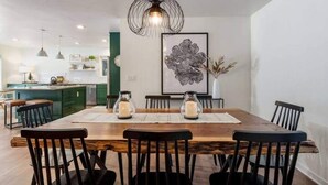 Een eetruimte met een houten tafel, zwarte stoelen en een moderne hanglamp.