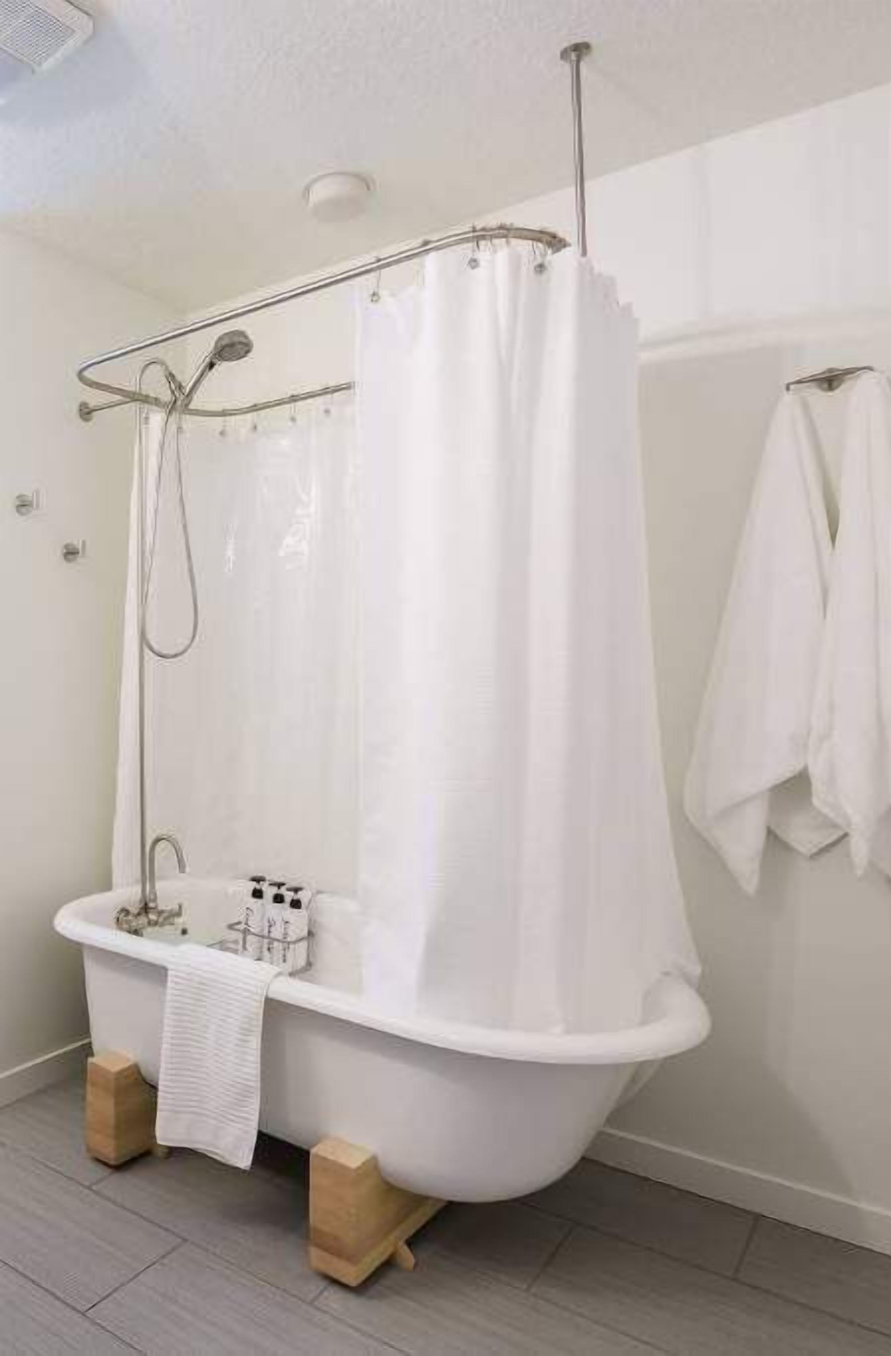 Un baño con una bañera blanca, una cortina de ducha y un perchero.