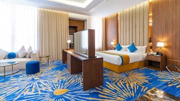 Une chambre d’hôtel comprenant un lit, une télévision, un bureau et un coin salon.