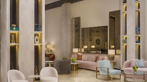 A modern living room with a sofa, armchairs, and a coffee table. There are shelves with decorative items and a large mirror. - Novo Hotel Riyadh (Riyadh)