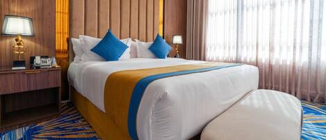 Een hotelkamer met een groot bed, twee nachtkastjes, een lamp en een kamerbreed tapijt met dessin.