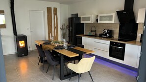 A modern kitchen with a central island, black appliances, and a wood-burning stove.