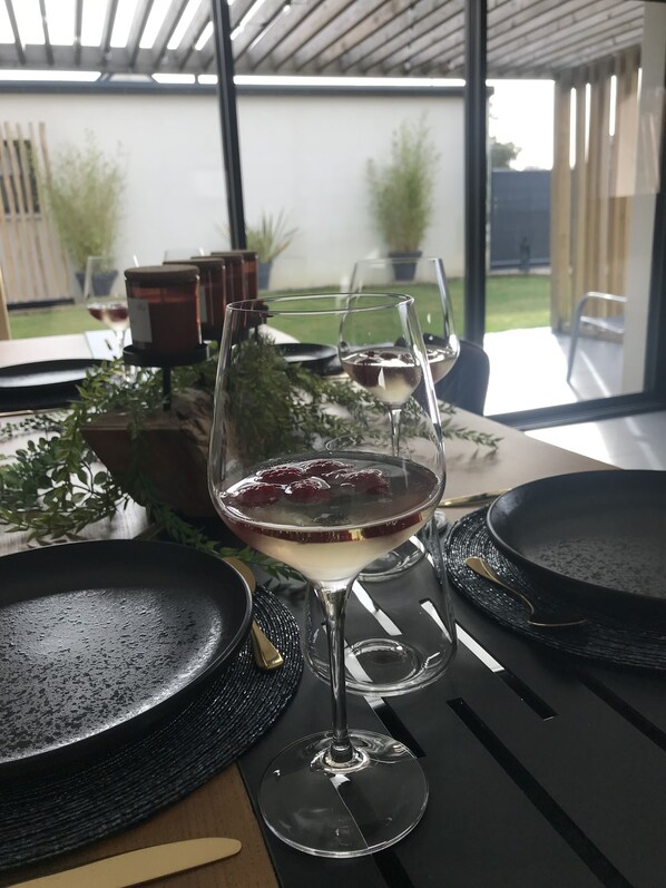A table set for dining with a glass of red wine and a martini glass, a black pan, and a woven placemat. - Villa de Plain-pied Avec Jacuzzi à Deux pas de la mer et du Centre Ville (Ploufragan)