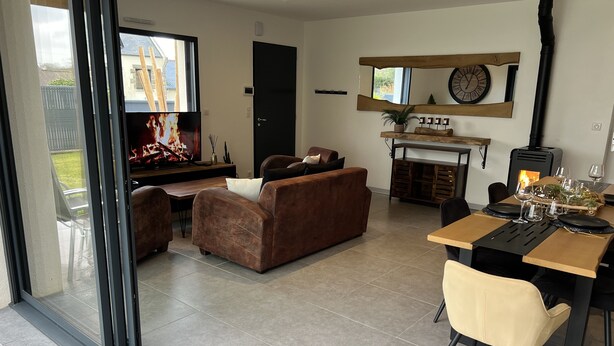 A modern living room with a fireplace, a dining area, and a large window.