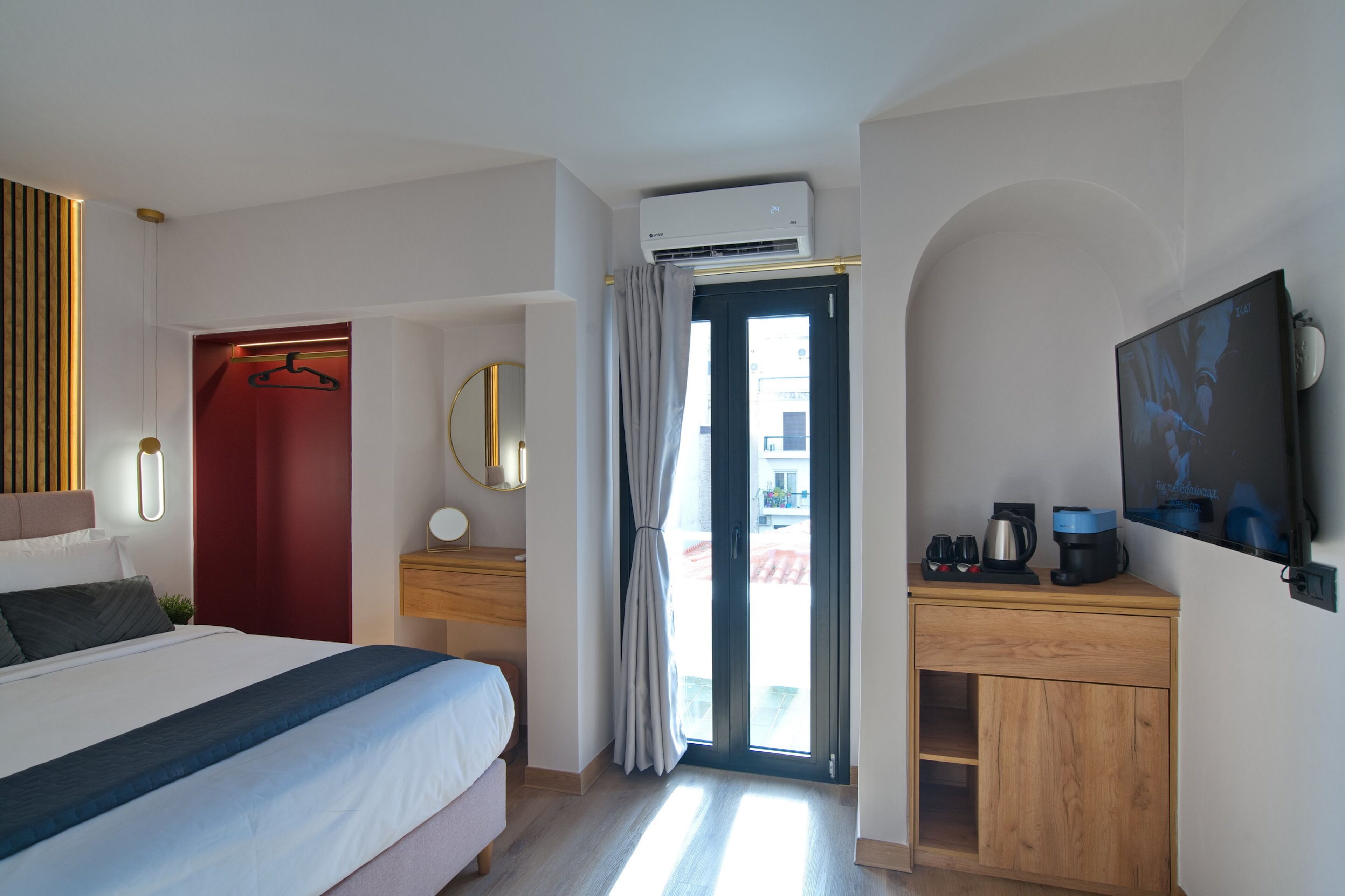 Habitación de hotel moderna con una cama, un escritorio de madera, un televisor y una puerta corrediza de vidrio al exterior.
