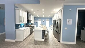 A modern kitchen with white cabinets, a central island, and a stainless steel refrigerator.